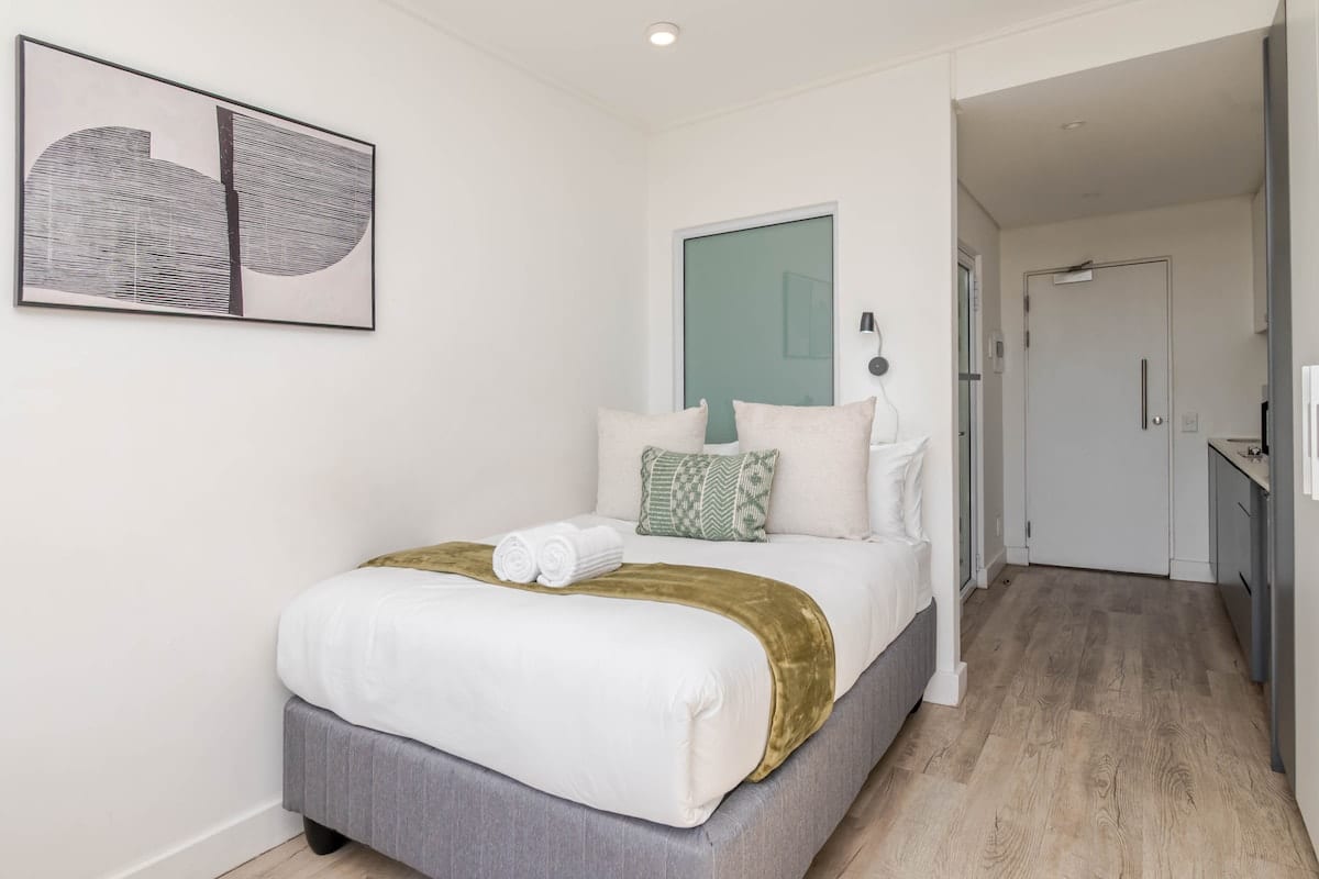 Queen bed with framed artwork and the entrance beyond